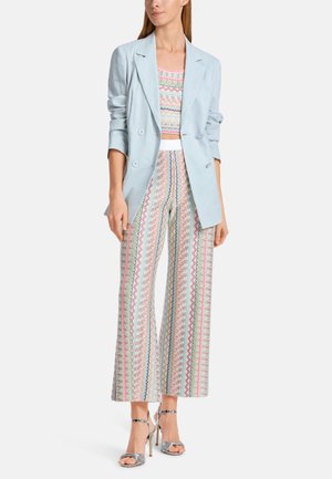 Light blue linen blazer over a patterned crop top and wide-leg pants featuring multicolored zigzag designs, paired with silver heeled sandals.