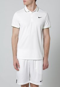 Biały podkoszulek polo z zielonym i czarnym wykończeniem, krótkie rękawy i logo Nike na lewej piersi, w zestawie z pasującymi białymi szortami.