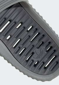 Gray slip-on sandal featuring a textured footbed with horizontal and vertical grooves. Includes a discreet embossed logo. Soft material.