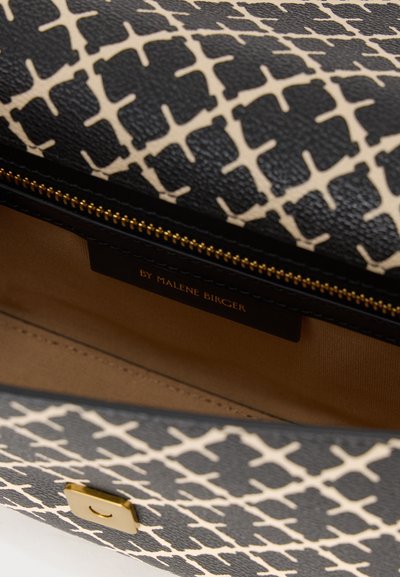 Δερμάτινη τσάντα με μοτίβο σε μαύρο και κρεμ, με χρυστό φερμουάρ και διακοσμητικά. Το εσωτερικό είναι από ταμπά ύφασμα με ευδιάκριτη ετικέτα, "By Malene Birger."