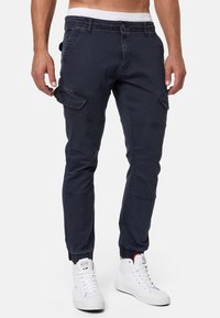 Pantalones cargo de la marina con múltiples bolsillos laterales, diseño entallado, puños elásticos y fabricados en una mezcla de algodón.