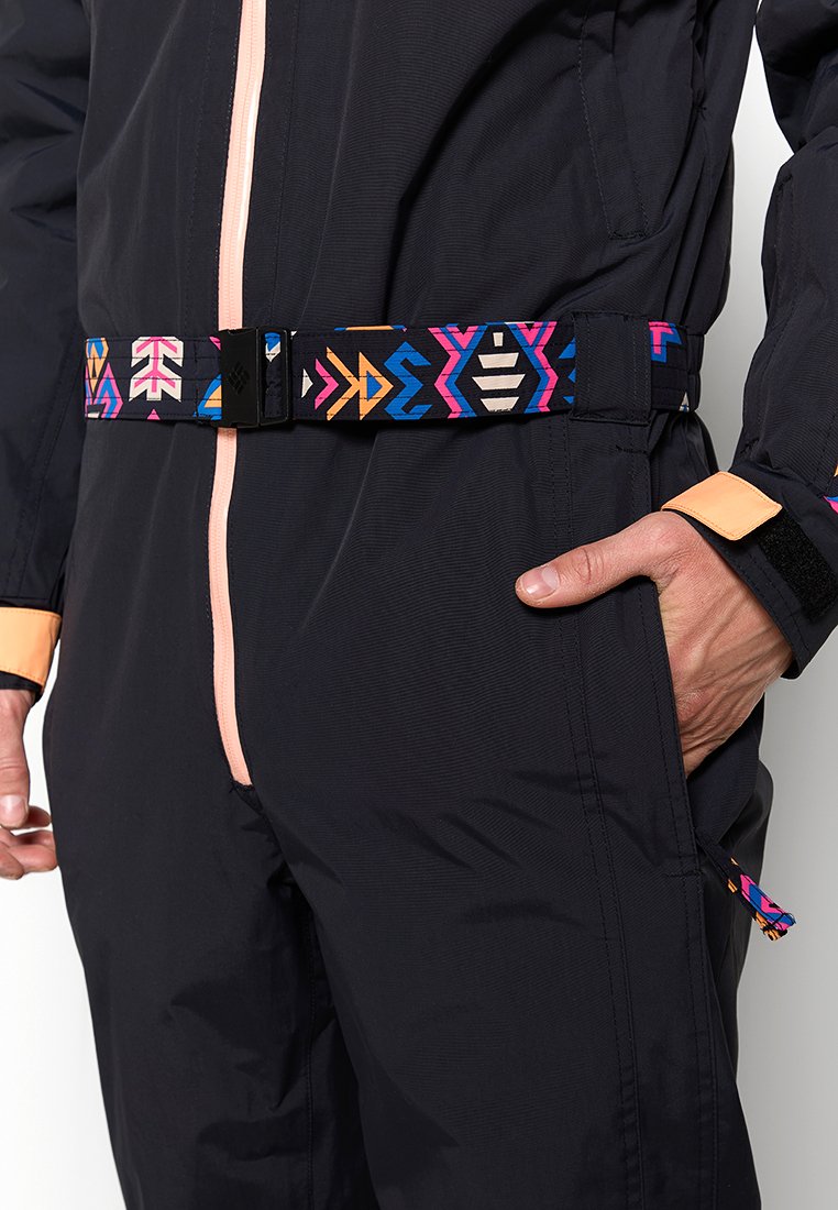 Czarny jednoczęściowy garnitur z różowym zamkiem błyskawicznym i graficznym paskiem z geometrycznymi wzorami w kolorach różowym, pomarańczowym, niebieskim i białym. Zawiera regulowany mankiet.