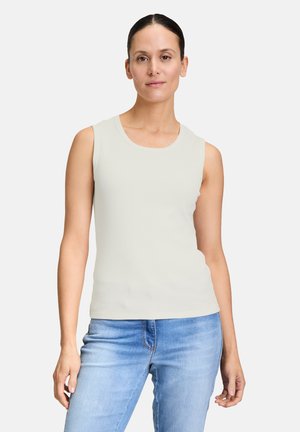 Haut sans manches gris clair avec un col rond, fabriqué en tissu côtelé. Associé à un jean bleu, mettant en valeur une silhouette ajustée.