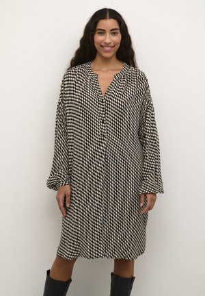 Robe à manches longues avec un motif en damier noir et crème, boutonnière à l'avant, tissu doux, coupe décontractée et ourlet arrondi.