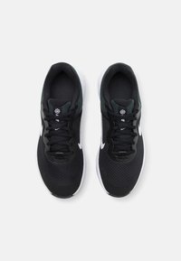Zapatillas deportivas negras con parte superior de malla, acentos blancos y cordones negros. Punta redonda, cuello acolchado y suela texturizada para tracción.