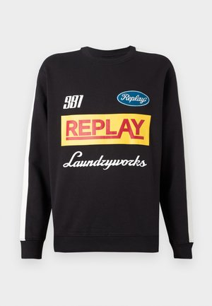 Black crewneck sweatshirt with white stripes on sleeves, featuring multicolored "Replay" and "Laundryworks" text logos on the front.