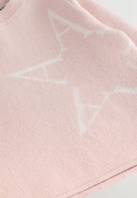 Svetlorožový sveter s jemnou textúrou a výrazným bielym hviezdicovým vzorom. Hladký okraj pri krku a upravené lemovanie.