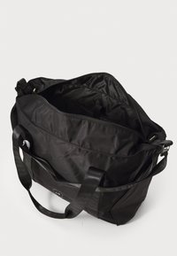 Black duffle bag made of durable fabric, featuring two sturdy handles, a zippered top, and a spacious interior with a smooth texture.