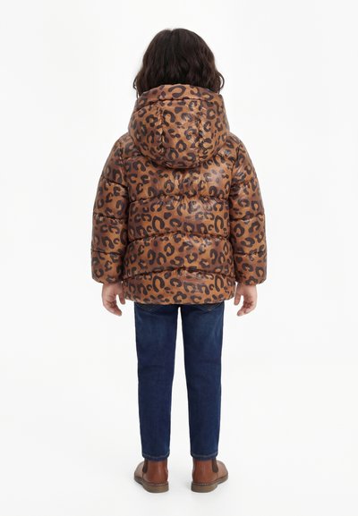 Dieťa stojace chrbtom, oblečené v hnedej prešívanej bunde s leopardím vzorom a kapucňou, modré rifle a hnedé topánky na bielom pozadí.