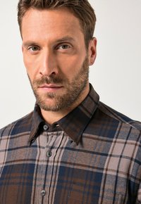 Braun-blau kariertes Hemd mit Button-Down-Kragen, das kontrastierende Muster und eine Tasche aufweist. Strukturierter Stoff.