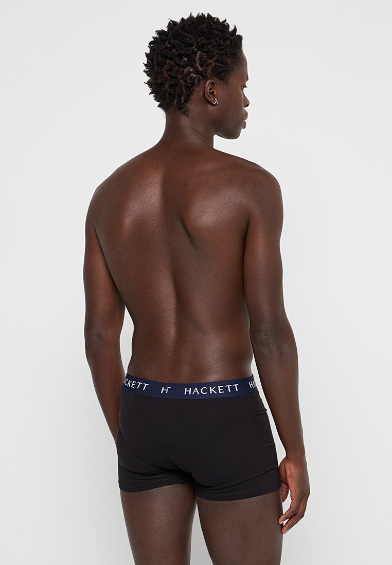 Boxer ajustados negros con una cinturilla elástica azul marino que presenta el logo en blanco "HACKETT". Material de algodón, forma ajustada y textura suave.