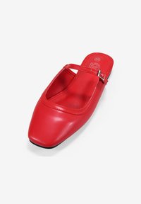 Zapato rojo de cuero tipo slip-on con puntera cuadrada, correa estrecha y detalle de hebilla; textura lisa con costuras mínimas y suela negra.