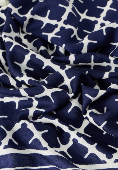 Ύφασμα σε ναυτικό μπλε με λευκά αφηρημένα σχέδια. Η υφή φαίνεται απαλή και ρέει χαλαρά, αναδεικνύοντας τον ευέλικτο σχεδιασμό και την οπτική αντίθεση.