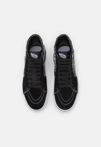 Czarne sneakersy za kostkę z zamszowego materiału, białym przeszyciem i wzorzystym wzorem po bokach. Posiadają czarne sznurówki i gumową podeszwę.