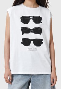 Camiseta de tirantes blanca con una ilustración gráfica de tres gafas de sol negras apiladas, con el texto "GAFAS DE SOL ALLSAINTS A OSCURAS" debajo.