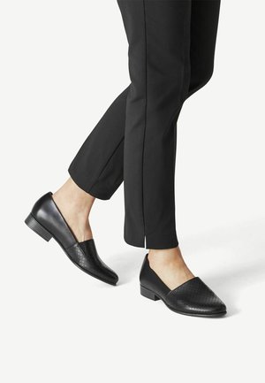 Chaussures plates noires avec un avant texturé et tissé et un talon lisse. Talon carré bas et design sans lacets qui complètent un pantalon noir sur mesure.