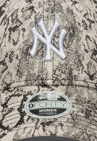 Boné ajustável bege com padrão de estampa de cobra preta, com o logótipo bordado dos New York Yankees em azul claro e um rótulo circular a dizer "9FORTY WOMEN."