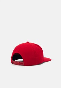 Red baseball cap made of fabric, featuring a curved brim, adjustable plastic strap at the back, and a solid color without patterns.