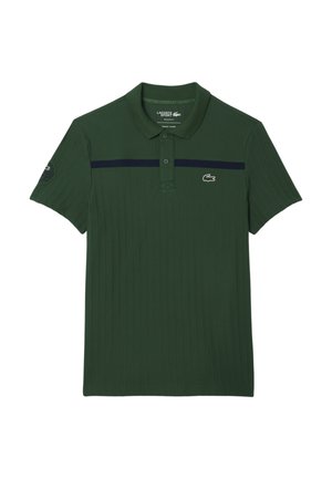 Camisa polo de color verde oscuro con textura acanalada, franja horizontal en color marino en el pecho, tapeta de tres botones y logo de Lacoste a la izquierda.