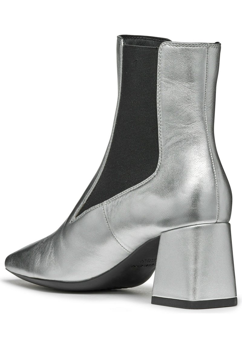 Silberne metallische Ankle Boots mit spitzem Zehenbereich, elastischen Seitenteilen und einem chunky Blockabsatz. Glatte Textur mit einem eleganten Finish.