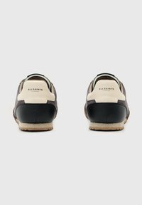 Sneaker in pelle nera e crema con finitura testurizzata, caratterizzate da una suola a contrasto e un sottile dettaglio del logo sul tallone.