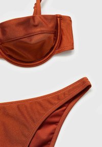 Costum de baie de culoare ruginie, format din sutien și chiloți dintr-un material neted și elastic; sutienul are cupe cu fir și bretele ajustabile; chiloții au un croi clasic.