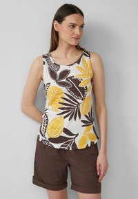 Débardeur blanc avec des motifs de feuilles jaunes et marron audacieux, col rond et sans manches, associé à un short marron retroussé.