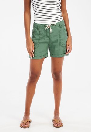 Groene katoenen shorts met opgerolde omzomen, zijzakken en een verstelbare trekkoord taille, gecombineerd met een gestreepte mouwloze top en sandalen.