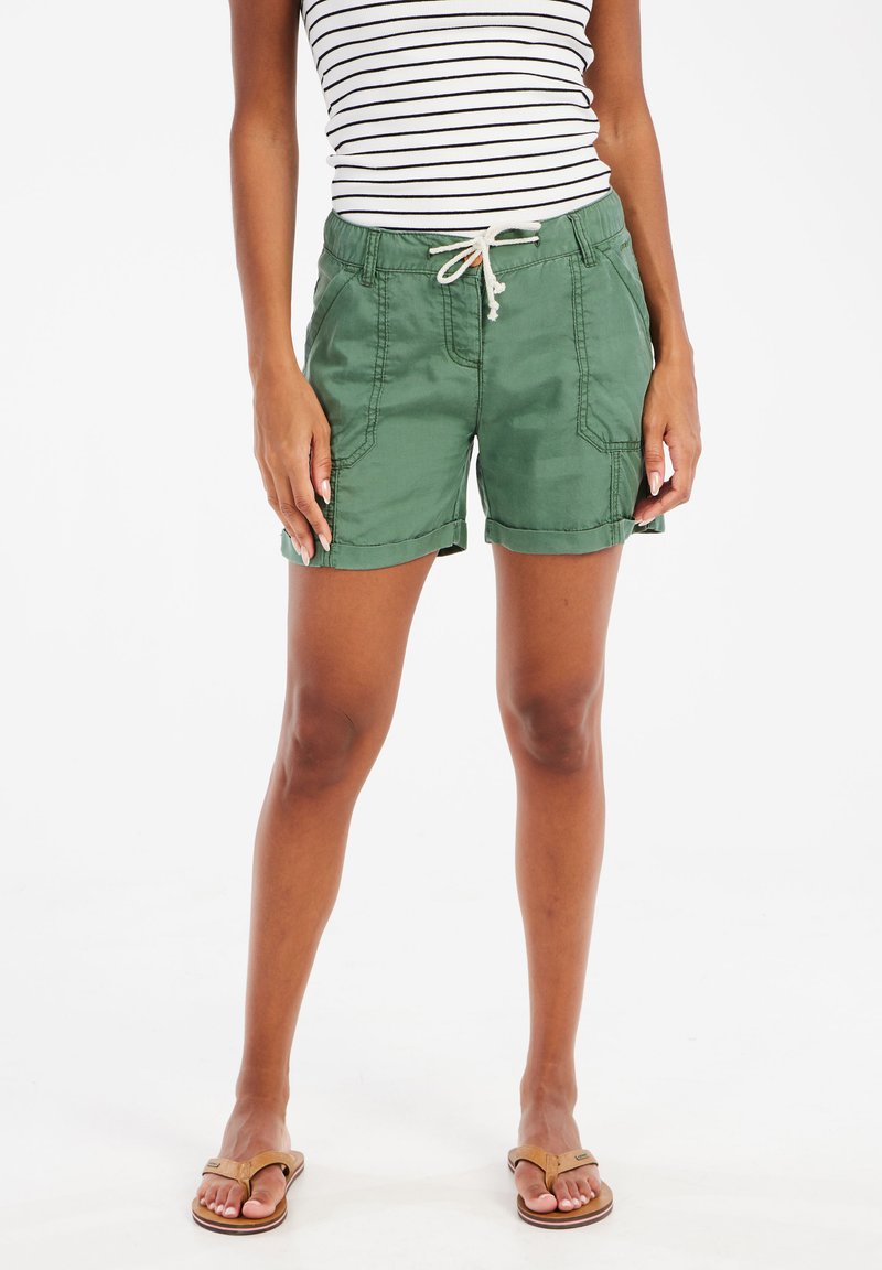 Groene katoenen shorts met opgerolde omzomen, zijzakken en een verstelbare trekkoord taille, gecombineerd met een gestreepte mouwloze top en sandalen.