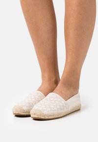 Le scarpe espadrillas bianche slip-on presentano una toma a motivi e una suola in corda di juta testurizzata. Il design è minimalista con punta arrotondata.