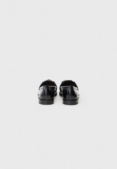 Black leather shoes with a smooth finish, featuring a low heel and decorative lacing detail at the back. Shiny surface and rounded toe.