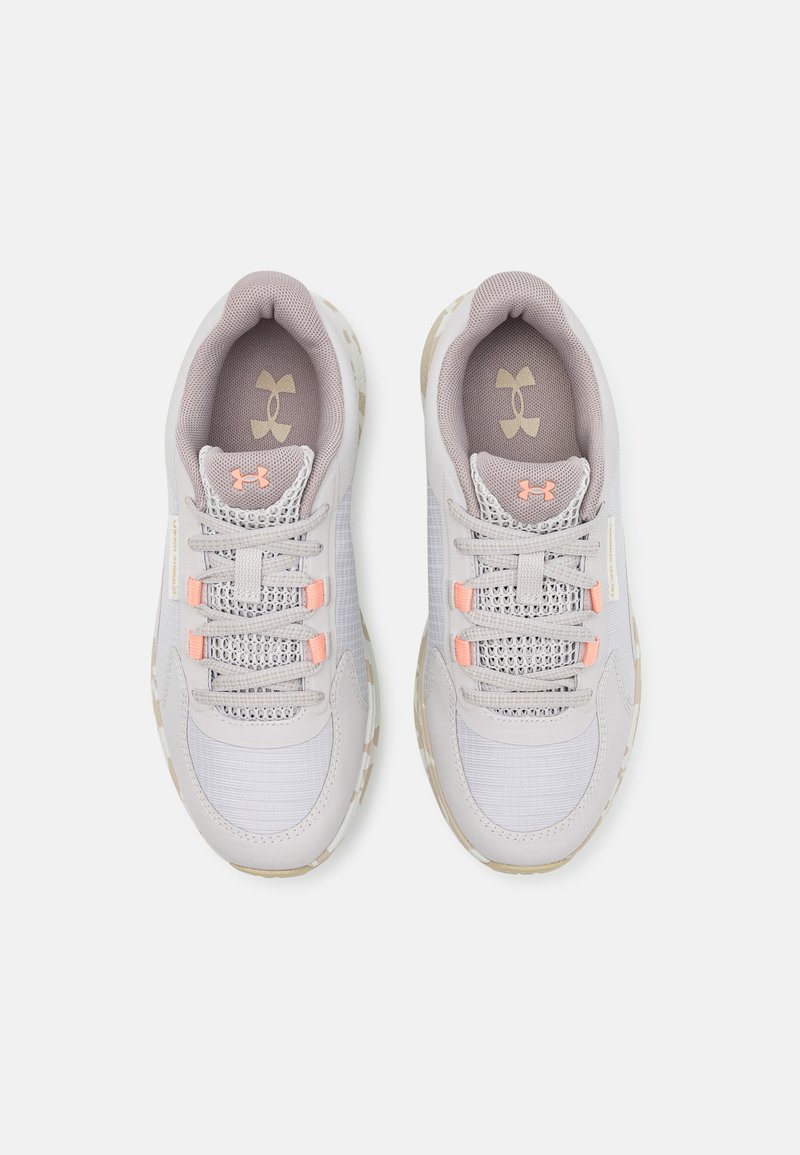 Scarpe sportive grigie con tomaia in mesh e accenti testurizzati, dotate di lacci rosa chiaro e suola beige. Logo Under Armour sulla linguetta.