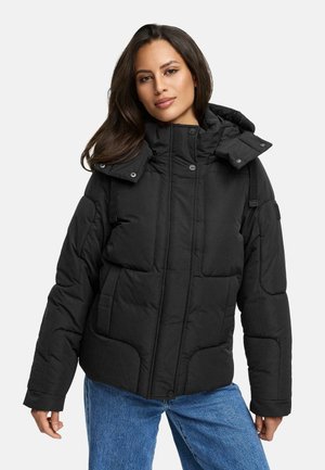 Black insulated puffer jacket with a hood, featuring a quilted design, snap closures, and two front pockets. Worn with blue denim jeans.