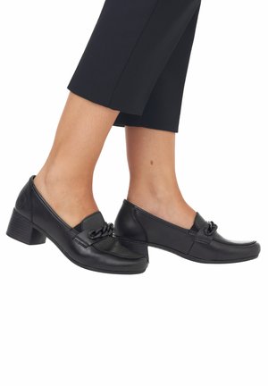 Black leather loafers with a low block heel, featuring a decorative chain detail across the front and smooth toe design.