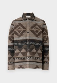 Camisa marrón abotonada hecha de lana con patrones geométricos en marrón oscuro, gris y negro. Cuenta con cuello y botones delanteros.