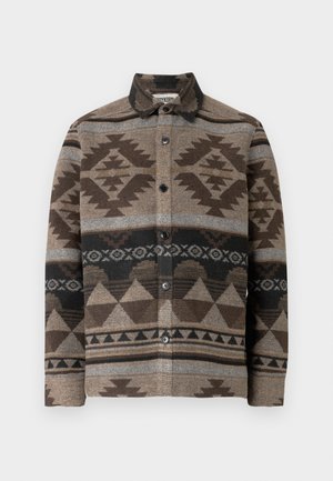 Hnědá košile zapínaná na knoflíky z vlny s geometrickými vzory v tmavě hnědé, šedé a černé barvě. Má límec a knoflíky na přední straně.