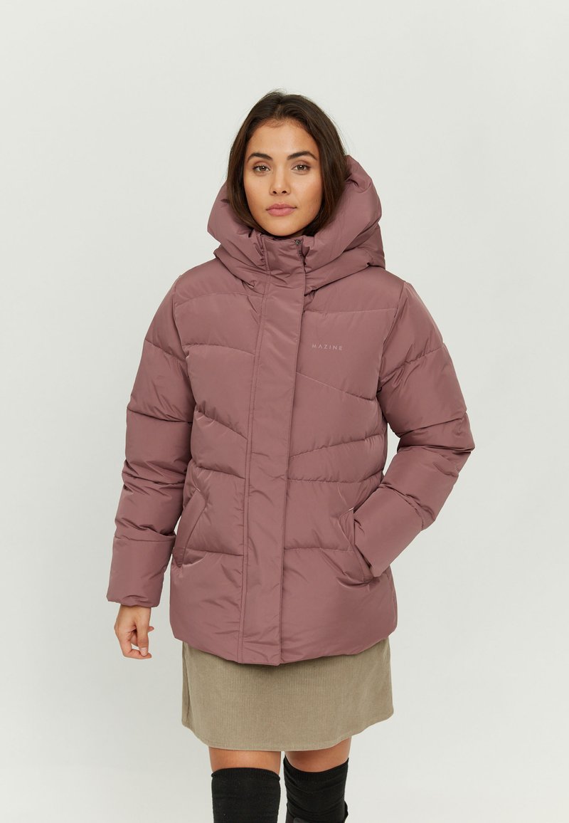 Puffer jacket in mauve with a high collar, detachable hood, quilted design, and front pockets. Worn over a beige skirt and knee-high socks.