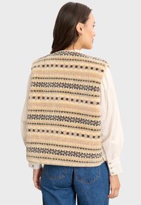 Fleece-Weste mit cremefarbigem Hintergrund, ausgestattet mit horizontalen Streifen in schwarzen und braunen geometrischen Mustern, abgerundeten Schultern und einem geraden Saum.