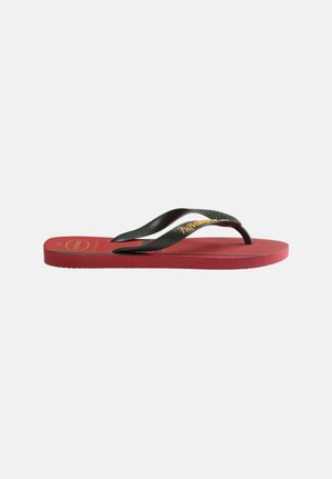 Infradito rossa in gomma con suola texturizzata e cinturini neri a forma di Y con marchio giallo "havaianas" su sfondo neutro.