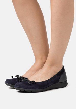 Ballerines en daim bleu marine avec une semelle en caoutchouc noire, dotées d'un détail en nœud au niveau des orteils et d'une finition en cuir lisse au talon.