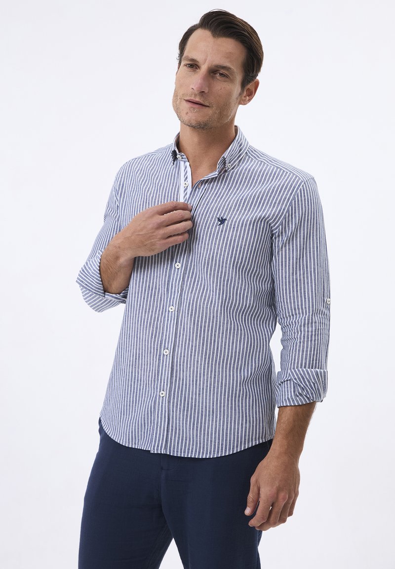 Camisa de dress de rayas en azul y blanco, fabricada en tela ligera, con cuello abotonado, logo bordado en el pecho, mangas enrolladas y un corte entallado.