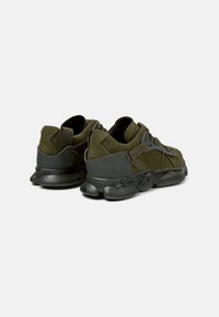 Zapatillas verde oliva con una combinación de materiales de ante y malla, que presentan una suela de goma texturizada y detalles de camuflaje en el talón.