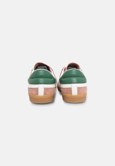 Paire de baskets basses en daim marron clair, détails en cuir vert au talon, bandes blanches et semelles en caoutchouc vues de dos.