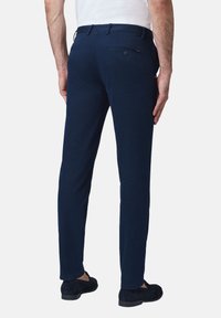 Granatowe spodnie wykonane z miękkiego materiału, o dopasowanym kroju, z szlufkami na pasek oraz tylną kieszenią zapinaną na guzik.