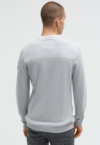 Hellgrauer strukturierter Pullover mit langen Ärmeln, gerippten Bündchen und Saum, mit einem horizontalen Strickmuster und einem kleinen rechteckigen Patch auf der Rückseite.