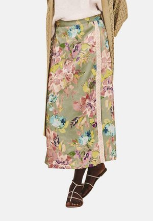 Falda floral de tela verde con flores rosas, azules y moradas; presenta un ribete trenzado a lo largo del costado. Se lleva con sandalias.