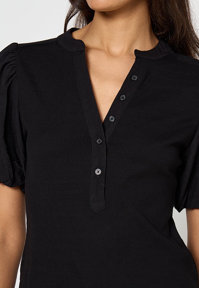 Top henley negro con canalé, cuello tipo collar, mangas cortas abullonadas y cierre de cinco botones en el pecho. Tejido suave con un acabado texturizado.