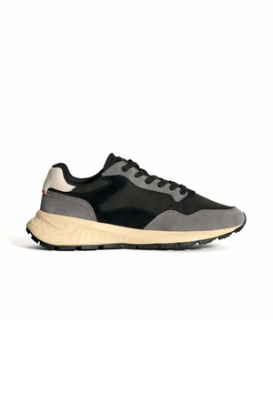 Des baskets grises et noires arborant un design en matériaux mixtes avec du daim et du mesh, une semelle beige rembourrée et une semelle extérieure en caoutchouc noir.