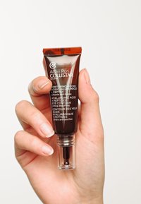 Brun tub med svarta accenter har en klar dispensertipp. Texten innehåller "Hyaluronsyra + Peptider" och "Ögonkontur."