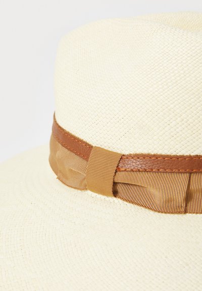 Breddebrimmet stråhatt med en teksturert, naturlig finish, pyntet med et brunt lærbånd og et beige bånd.